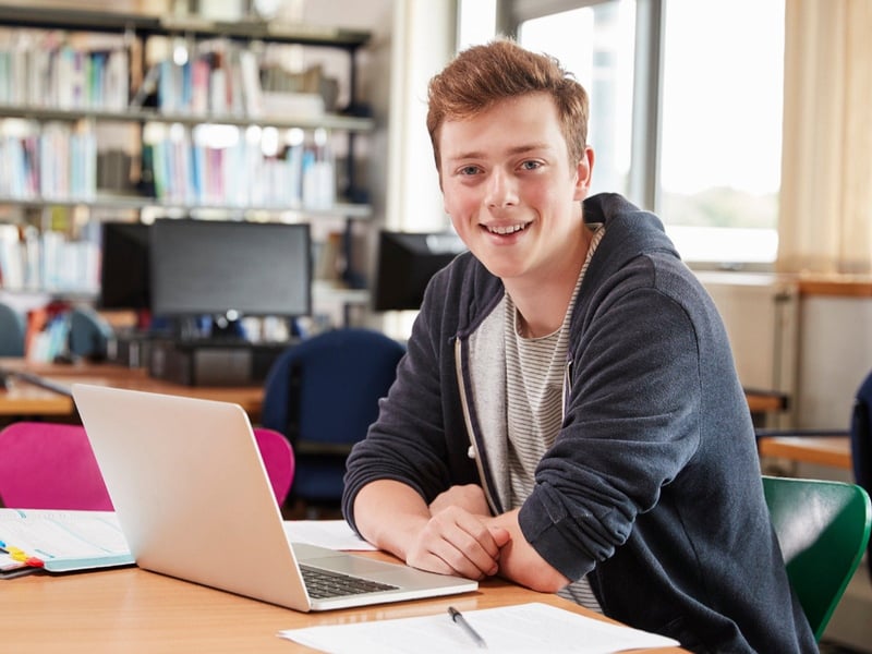 student on laptop looking at camera in library