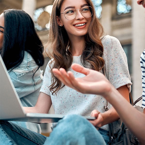 Student with laptop talking to a friend